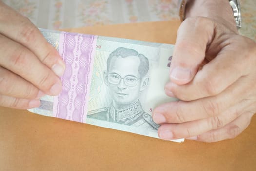 Man hand counting Thai baht banknote, stock photo