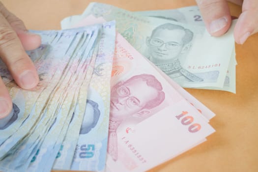 Man hand counting Thai baht banknote, stock photo