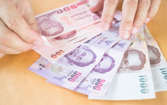 Man hand counting Thai baht banknote, stock photo