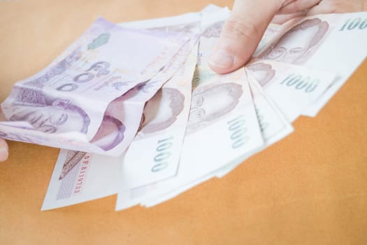 Man hand counting Thai baht banknote, stock photo