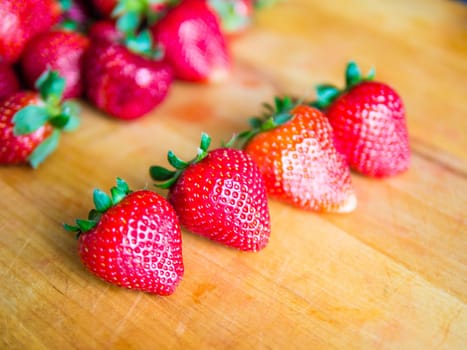 Row of fresh strawberries on a wooden board