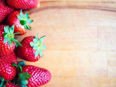 Arranged strawberries on a wooden board with empty space