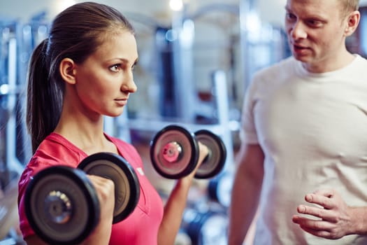 Portrait of young woman exercising with barbells in gym