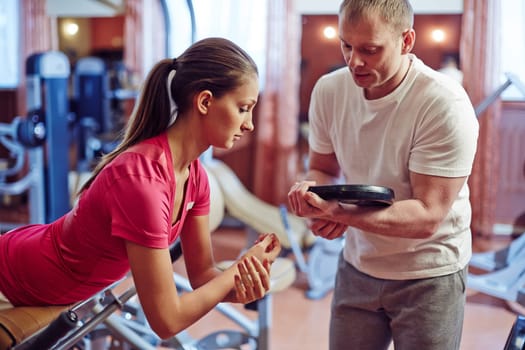 Fit girl exercising on facilities with her trainer near by