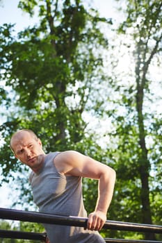 Young man in grey vest having outdoor workout