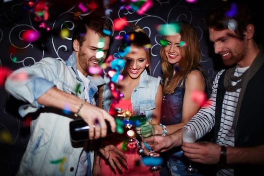 Cool guy pouring champagne in flutes of his friends