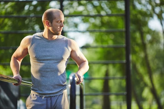 Sporty man in grey vest training in natural environment
