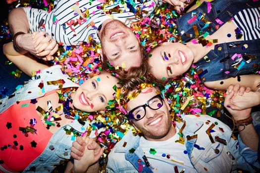 Cheerful friends lying on the floor in nightclub and looking at camera