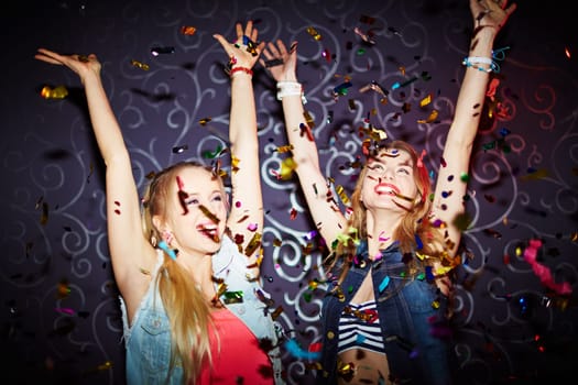 Two energetic girls dancing with raised arms