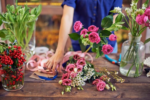 Fresh flowers and ripe berries with designer standing near by