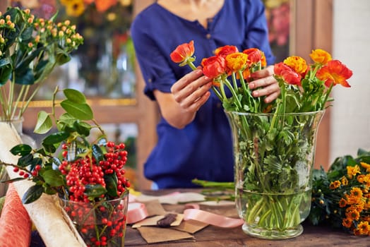 Female florist working with fresh flowers in design studio