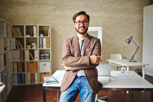 Asian businessman standing by his desk in office