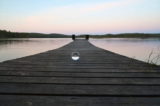 Glass ball on a wooden walkway on a Swedish lake at the blue hour. Nature shot from Scandinavia