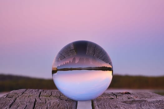 Glass ball on a wooden pier at a Swedish lake at evening hour. Nature shot from Scandinavia