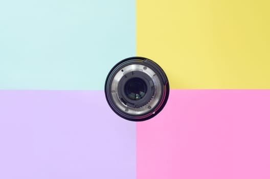 Minimalism with photographic lens on blue, violet, pink and yellow background. Trendy pastel colors. Flat lay top view