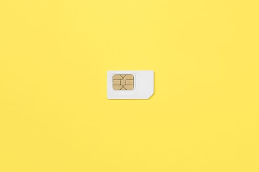 Subscriber identity module. New white SIM card on bright yellow color background. Minimal flat lay top view
