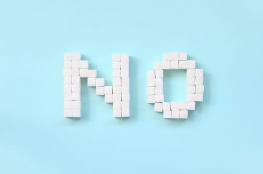NO Letters of sugar cubes on a pastel blue background. Diabetic concept. Refusing sugar. Flat lay minimal top view