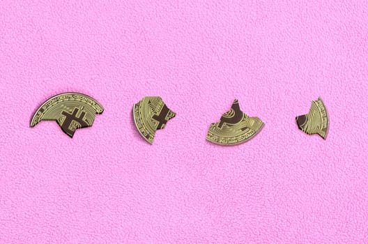 Broken into pieces bitcoin lying on a pink fleece fabric background. The fall and collapse of the course of crypto currency. Bad news for cryptocurrency investors.