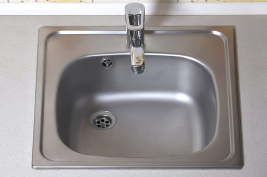 Sink with silver faucet. Built-In domestic kitchen appliances. New equipment installed in the kitchen counter