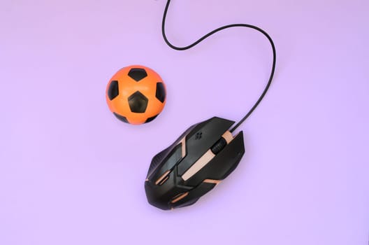 Soccer ball with computer mouse on violet background. Concept of videogames, eSports, sports betting and online gambling