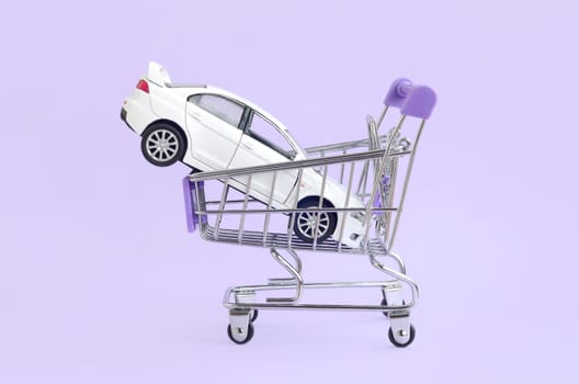 New white toy car in shopping cart as a symbol for car buying and leasing