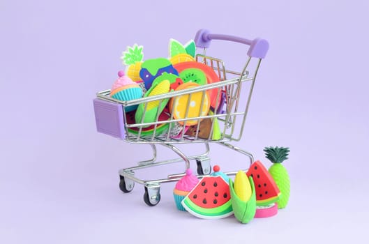 Shopping cart is filled to the top with fresh fruits on a purple background. The concept of buying food and fruit online. Diet food