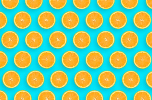 Top view of a orange fruit slices on bright blue background. A saturated citrus pattern. Minimalistic flat lay