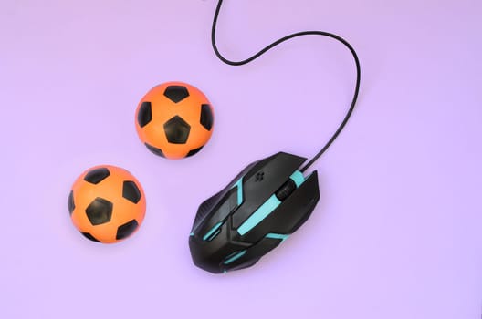 Two soccer balls with computer mouse on violet background. Concept of videogames, eSports, sports betting and online gambling