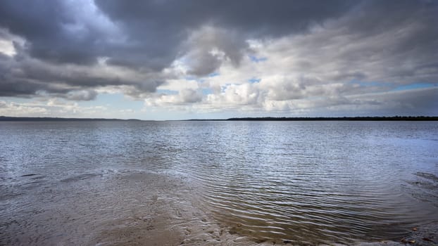 Dramatic storm clouds brewing over the sea and beach at Poona Beach, Queensland. Panorama looking across the Great Sandy Strait, along the Fraser Coast towards the horizon at Inskip Point, Rainbow Beach.