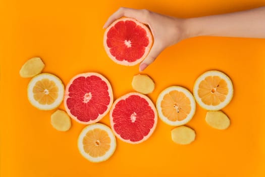 Top view of fresh slices of lemon, grapefruit and ginger on bright orange background