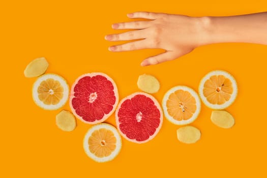 Top view of fresh slices of lemon, grapefruit and ginger on bright orange background