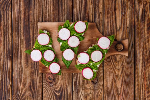 Top view of sandwiches with soft garlic cheese, basil and radish