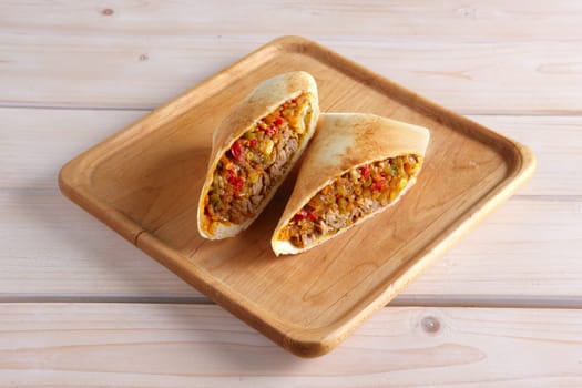 Burritos wraps with meat, beans and vegetables on wood board