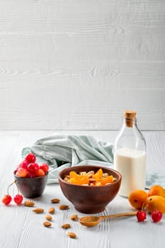 muesli with apricots and almonds on white wooden table