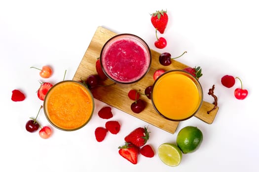 top view of three glasses with fruit smoothies on white background