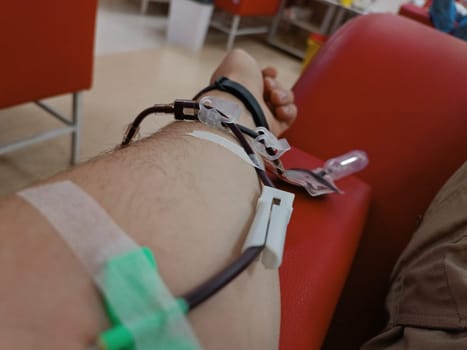 Blood donation, blood transfusion, check specified, fasting, health care. Left arm of caucasian young man with equipment for blood or plasma donations in donation centre. Blood donation concept. Plasma donation concept. Save life concept