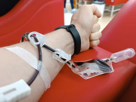 Blood donation, blood transfusion, check specified, fasting, health care. Left arm of caucasian young man with equipment for blood or plasma donations in donation centre. Blood donation concept. Plasma donation concept. Save life concept