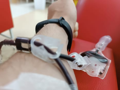 Blood donation, blood transfusion, check specified, fasting, health care. Left arm of caucasian young man with equipment for blood or plasma donations in donation centre. Blood donation concept. Plasma donation concept. Save life concept
