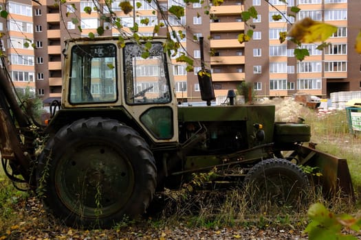New modern building in process with vintage tractor green color.