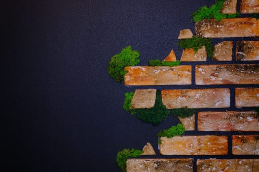Black wall with bricks in the green moss and wooden clock and warm light. Place for text. Banner concept