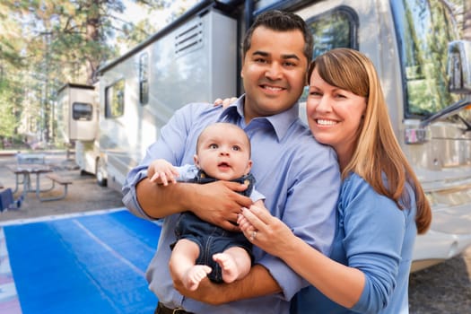 Happy Multiethnic Caucasian and Hispanic Couple with Baby In Front of Their Beautiful RV At The Campground.