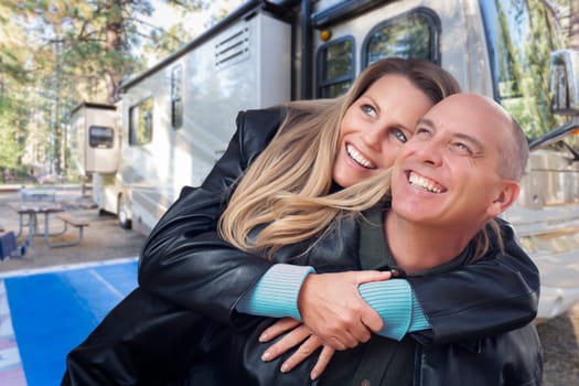 Happy Caucasian Couple In Front of Their Beautiful RV At The Campground.