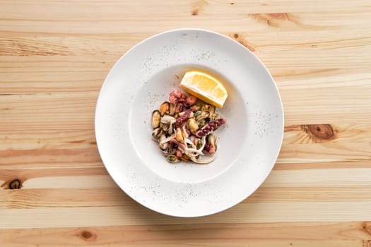 Salad with octopus, shrimps and mussels on wooden table
