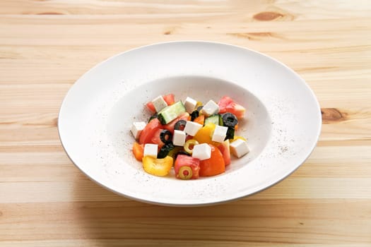 Salad with pepper, tomato, cucumber, olives and feta on wooden table