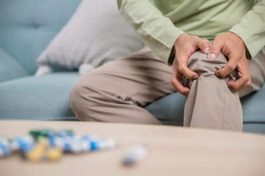 Old age. Asian senior man retirement knee joint pain on sofa, Elderly old man sitting down hands hold knee, Grandfather people health care bone problem at home