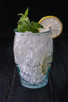 Cold cocktail with vodka and tonic in skull cup on dark wooden background