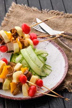 Shashlik with vegetables, mushrooms and mozzarella on dark wooden table