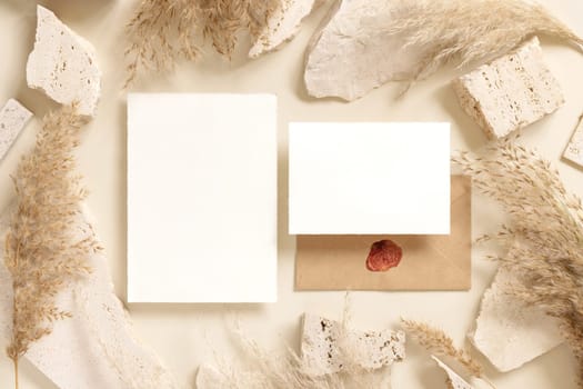 Blank cards near beige travertine stones and dried pampas grass top view, mockup. Boho scene. Bohemian or close to nature greeting or wedding Invitation. Close to nature.