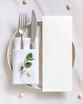 Elegant Table setting with card and envelope decorated with eucalyptus branches top view, Wedding Mockup. Romantic table with vertical paper card. Close to nature and simplicity concepts