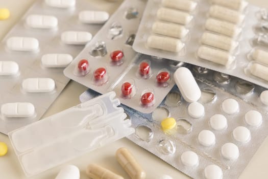 Mix of pills and capsules in a aluminum and plastic blisters with some missing pills already used on light beige close up. Preventive medicine and healthcare, taking dietary supplements and vitamins